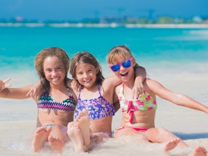 3 young girls sitting in shallow water on Seven Mile Beach