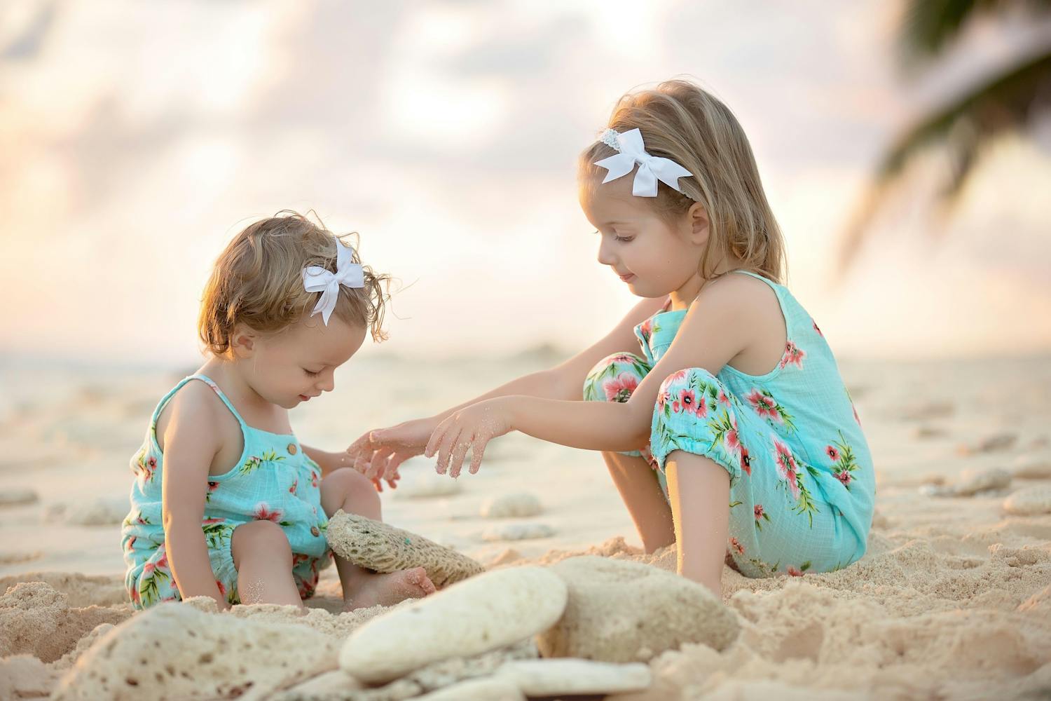 Baby and her young sister playing in the sand on the beach