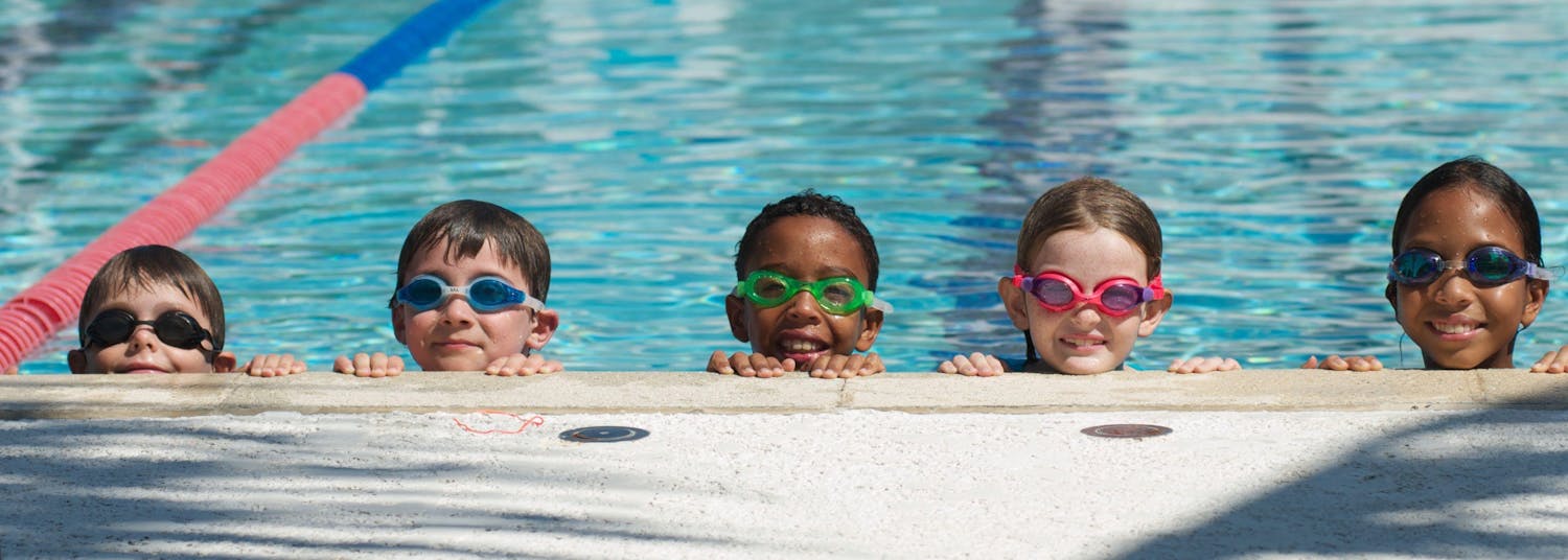 Five kids looking over the edge of large swimming pool