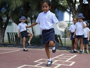 Kids playing hopscotch at school in uniform