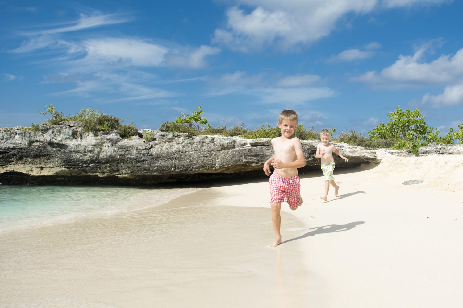 Kids running along the beach in the Cayman Islands