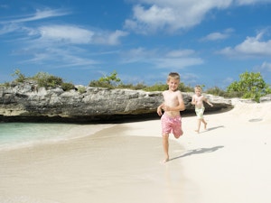 Kids running along the beach in the Cayman Islands