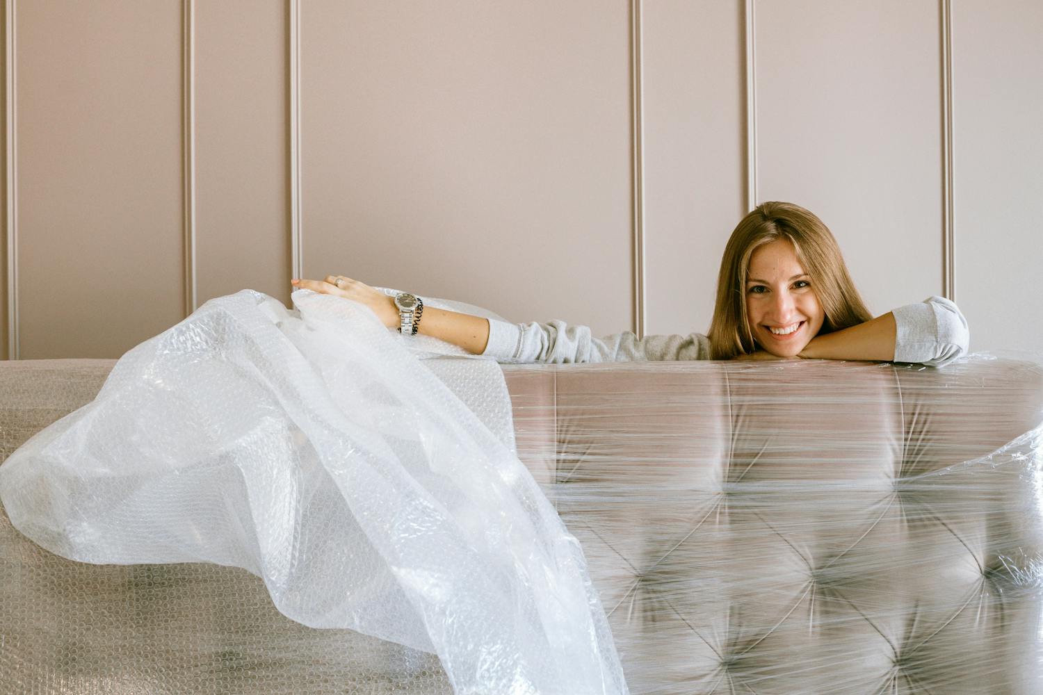 Lady unwrapping plastic off couch after moving