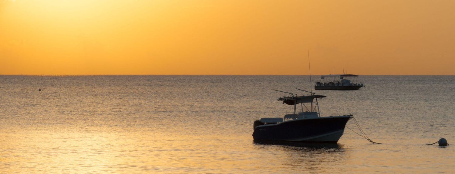 Small fishing boat anchored offshore during sunset