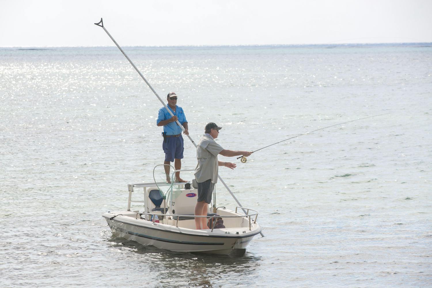 Two men fly fishing off small boat