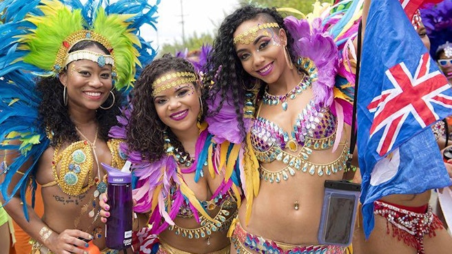 Beautiful women dressed up for carnival holding a cayman flag