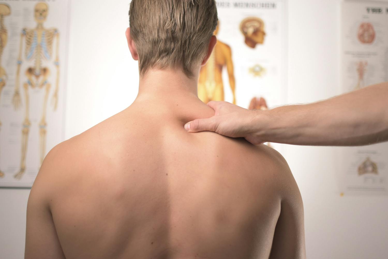 Chiropractor squeezing mans shoulder looking at charts