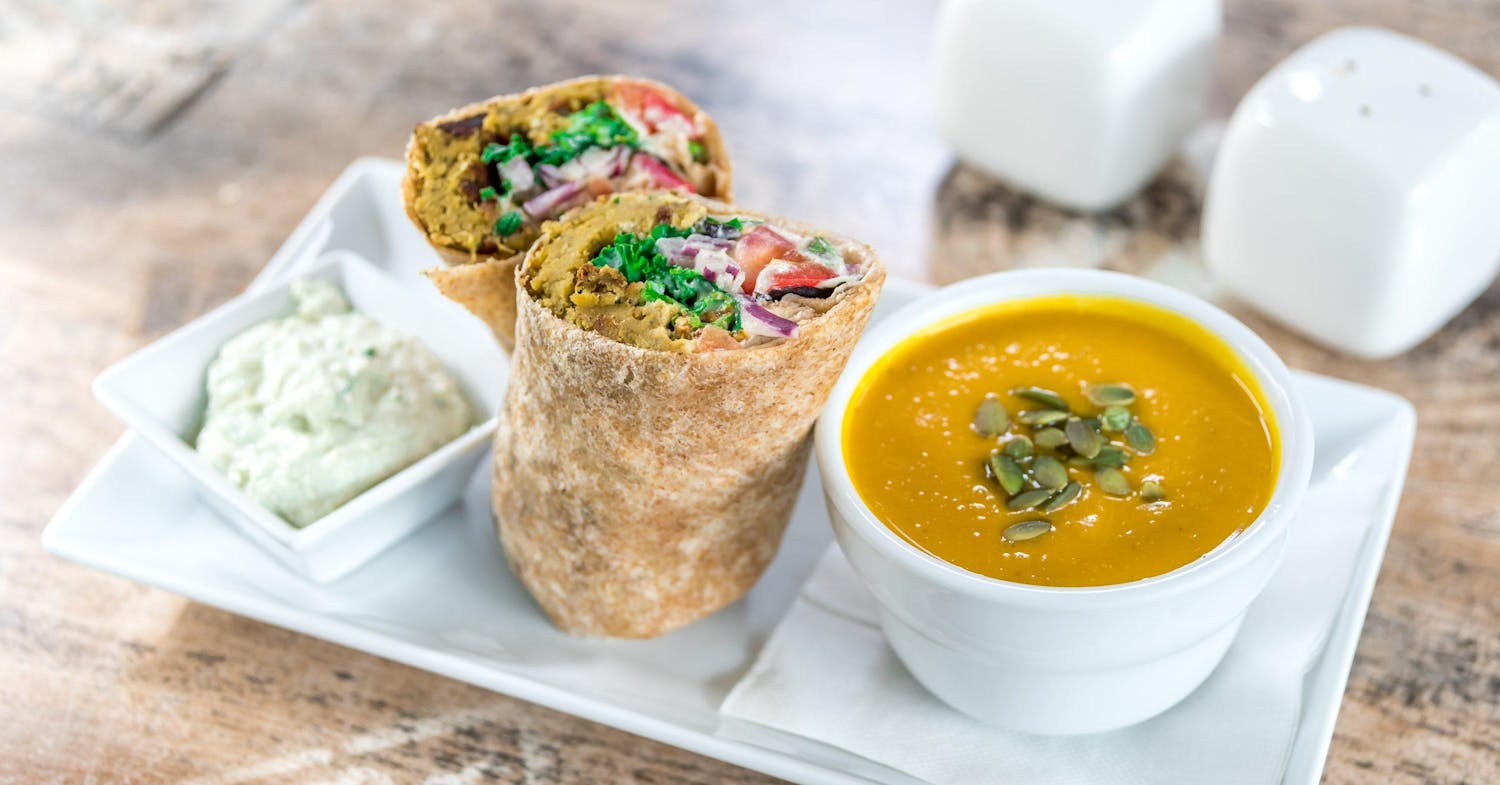 Delicious veggie wrap and soup on a white plate on an angle