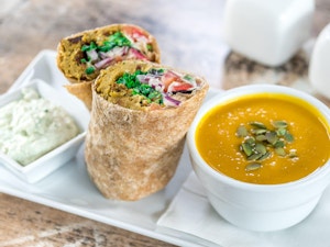 Delicious veggie wrap and soup on a white plate on an angle
