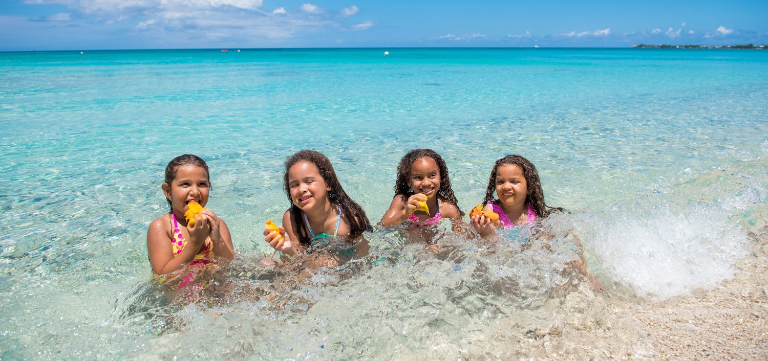 Four little girls eating mango seed in the ocean