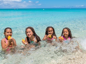 Four little girls eating mango seed in the ocean