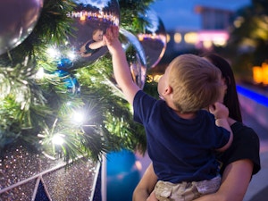 Little boy touching christmas decor on tree in camana bay