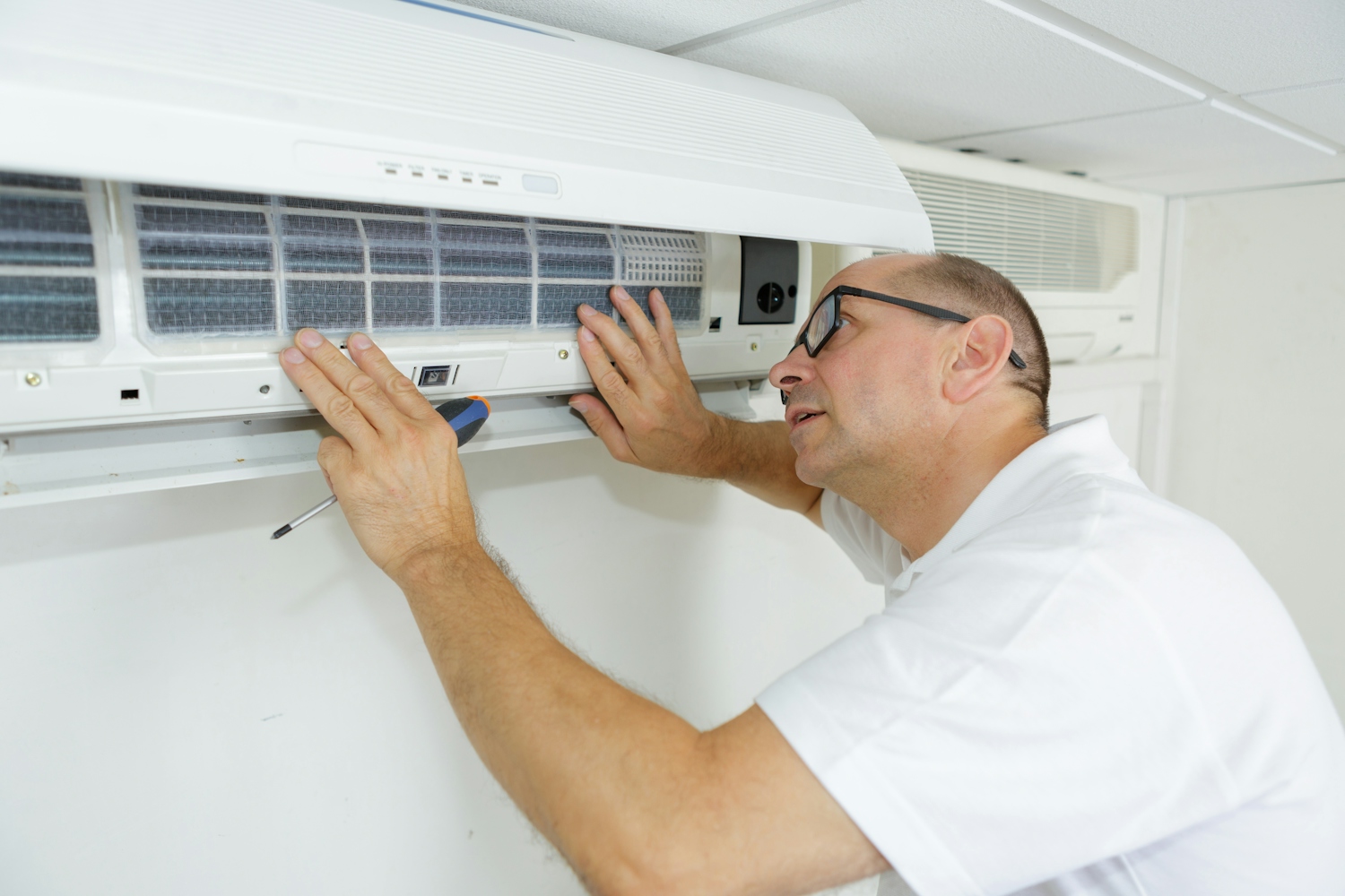 Man in white shirt fixing wall mounted air con