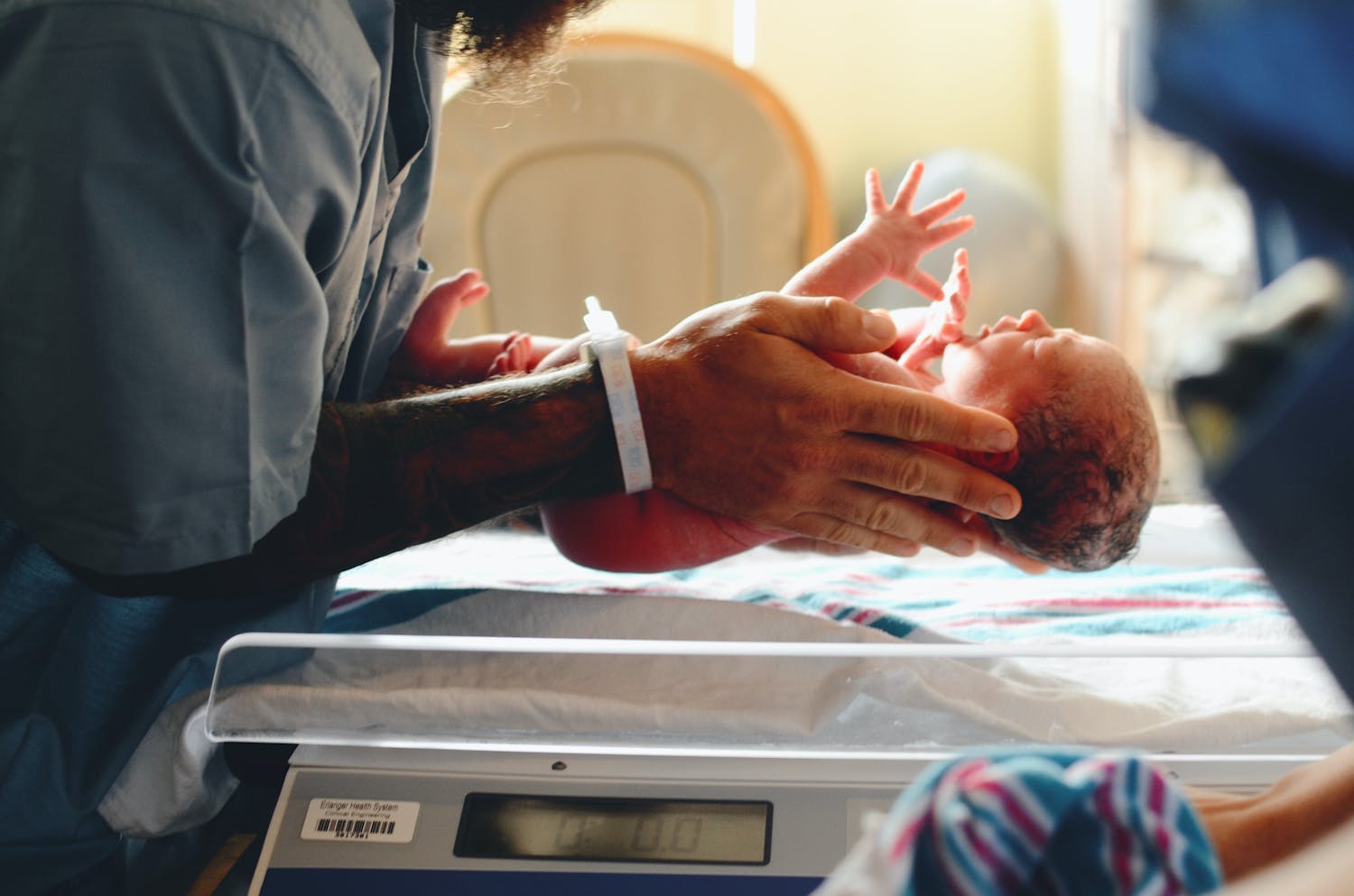 Newborn baby being weighed by a nurse