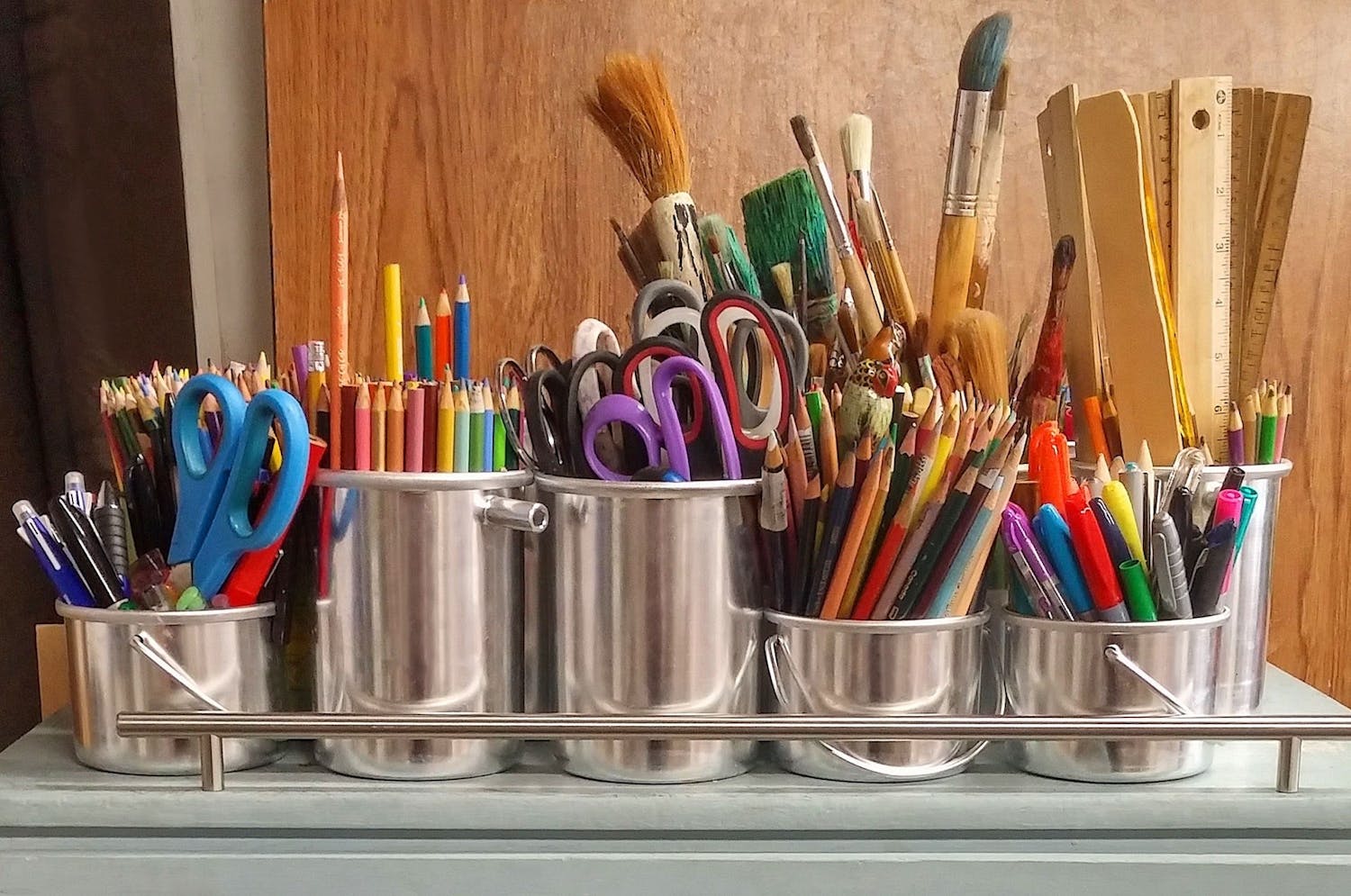 Pencils and paint brushes in stainless steel bucket