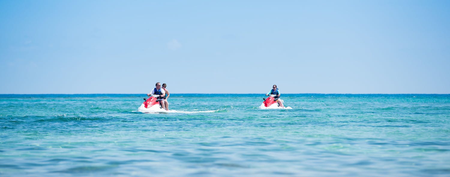 Three people enjoying the afternoon jetskiing on the beautiful blue ocean