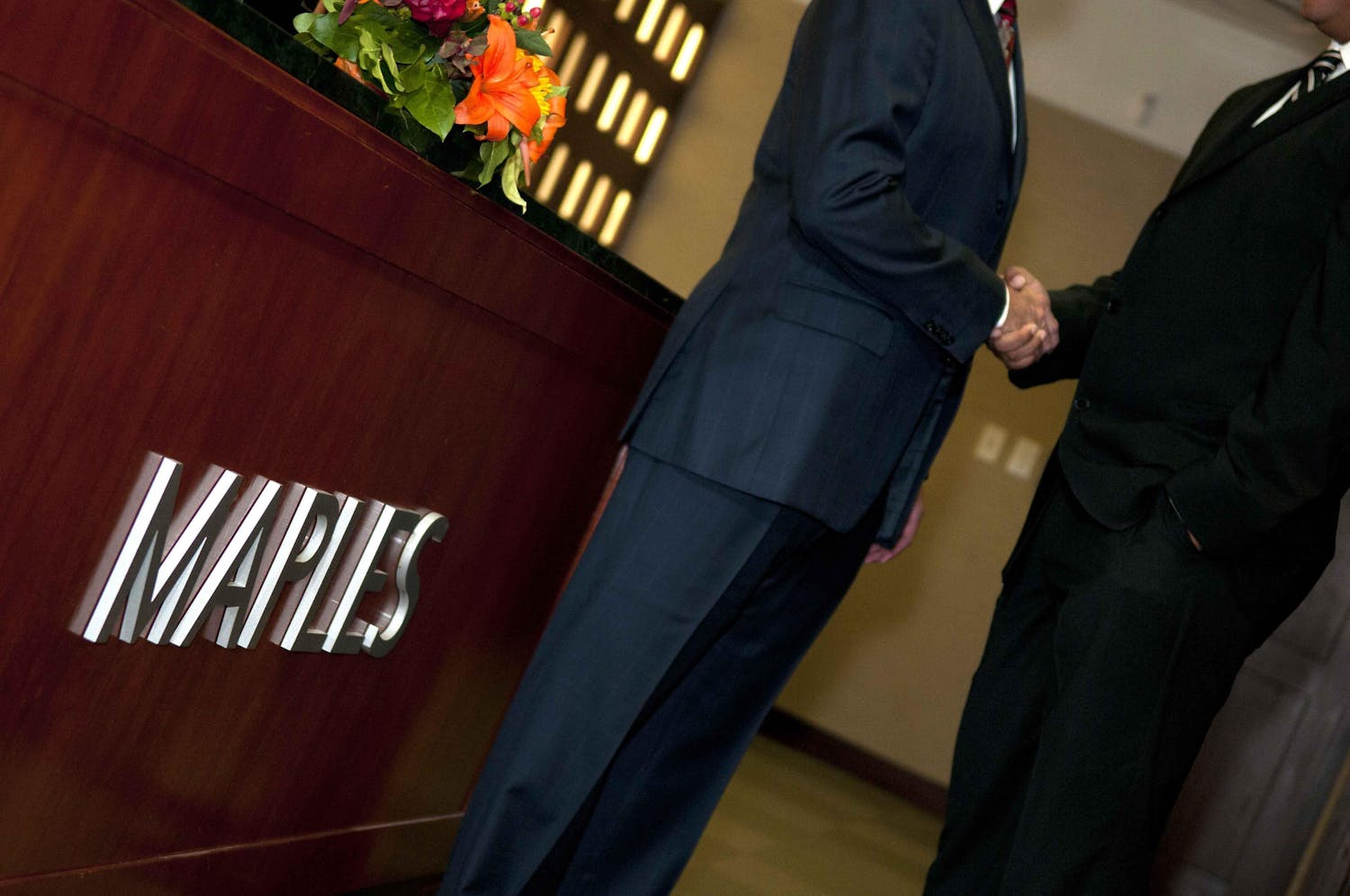 Two businessmen shaking hands outside the maples office