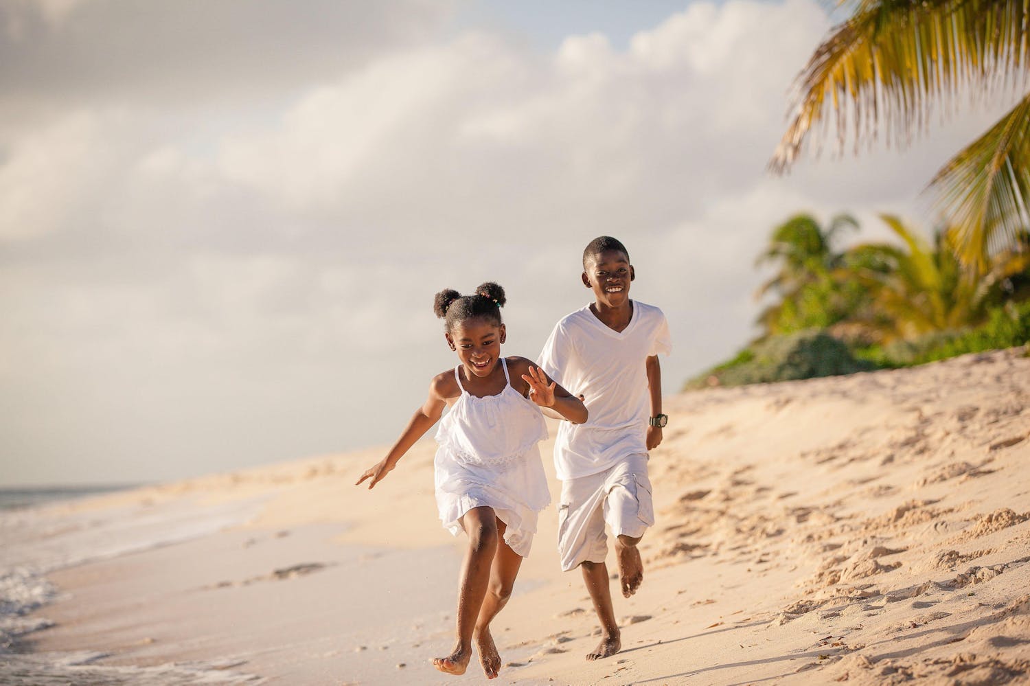 Two children running down the beach laughing
